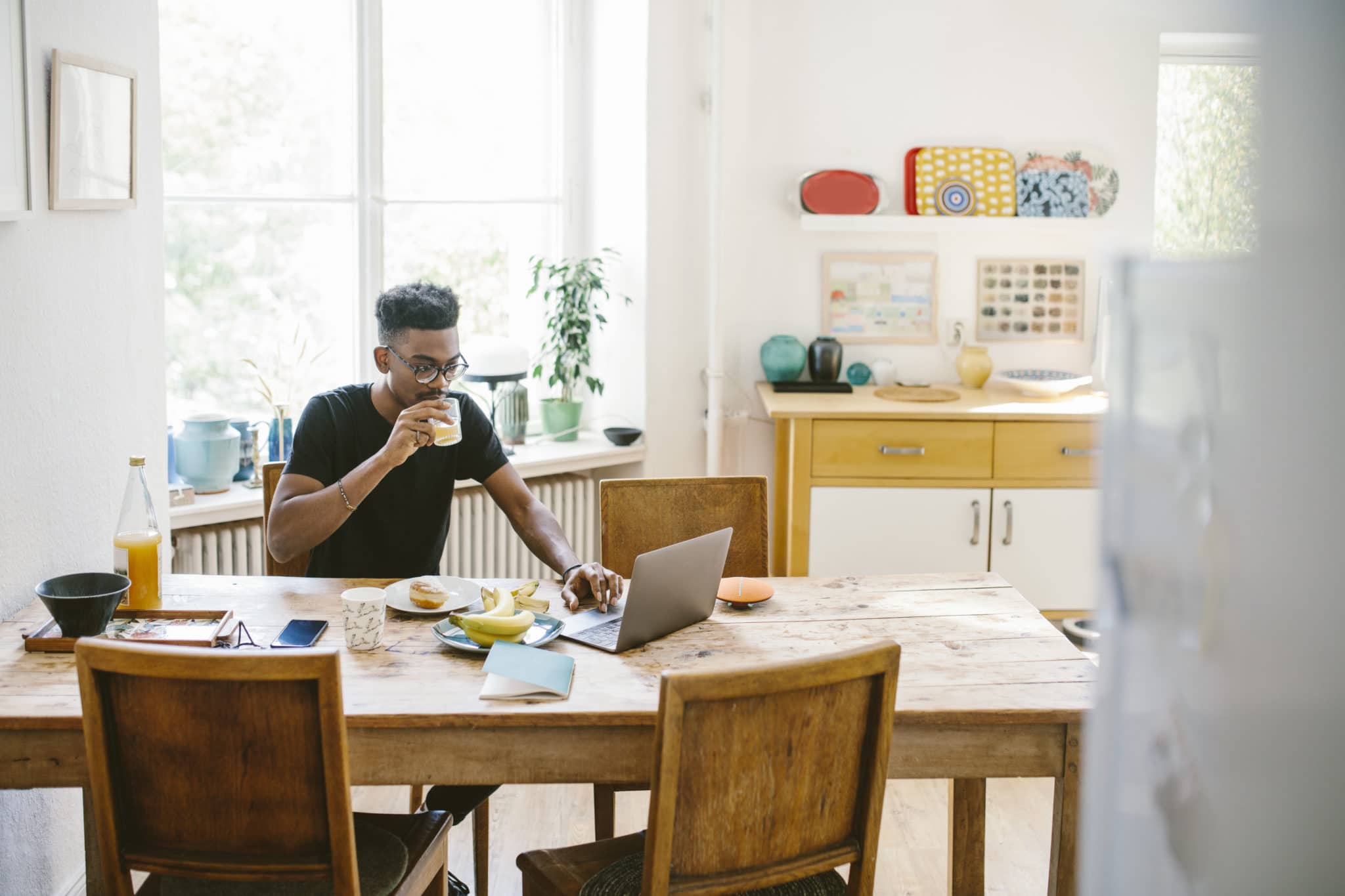 Man eating breakfast and working on laptop.